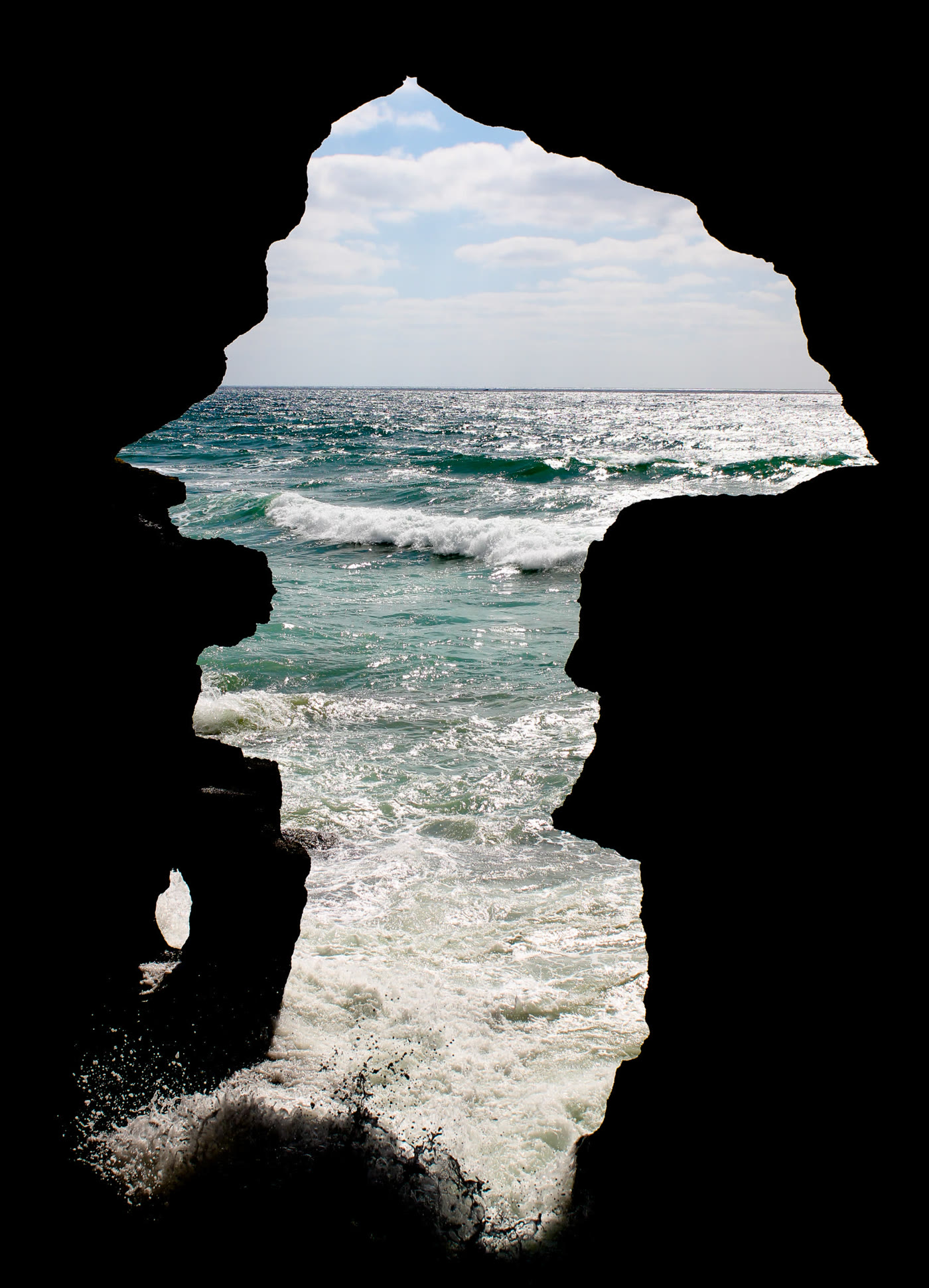 The cave opening at the Caves of Hercules, its silhouette famously shaped like the map of Africa, framing the Atlantic Ocean