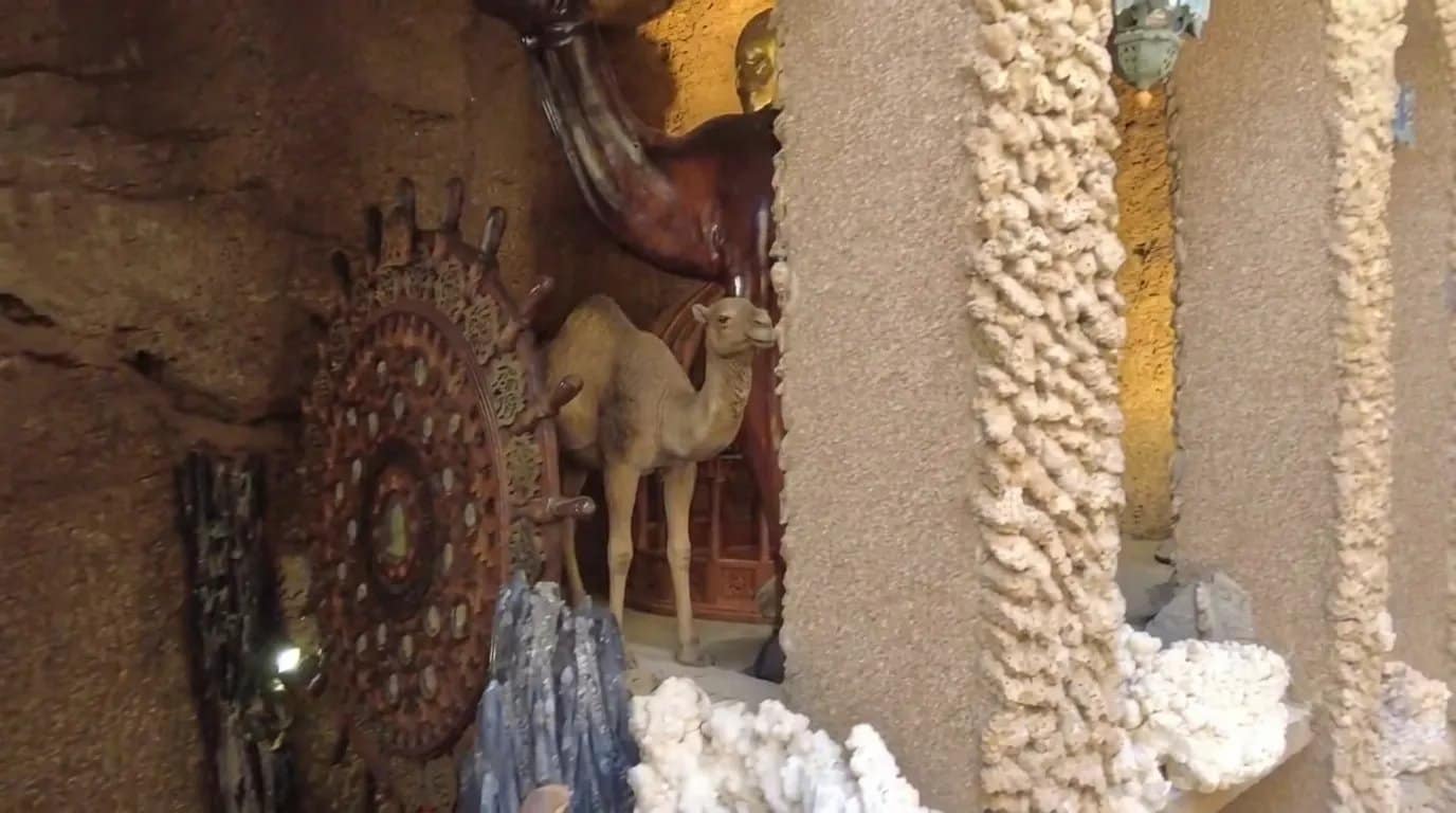 A wooden camel sculpture and carved wooden wheel in the decorated chamber of the Caves of Hercules